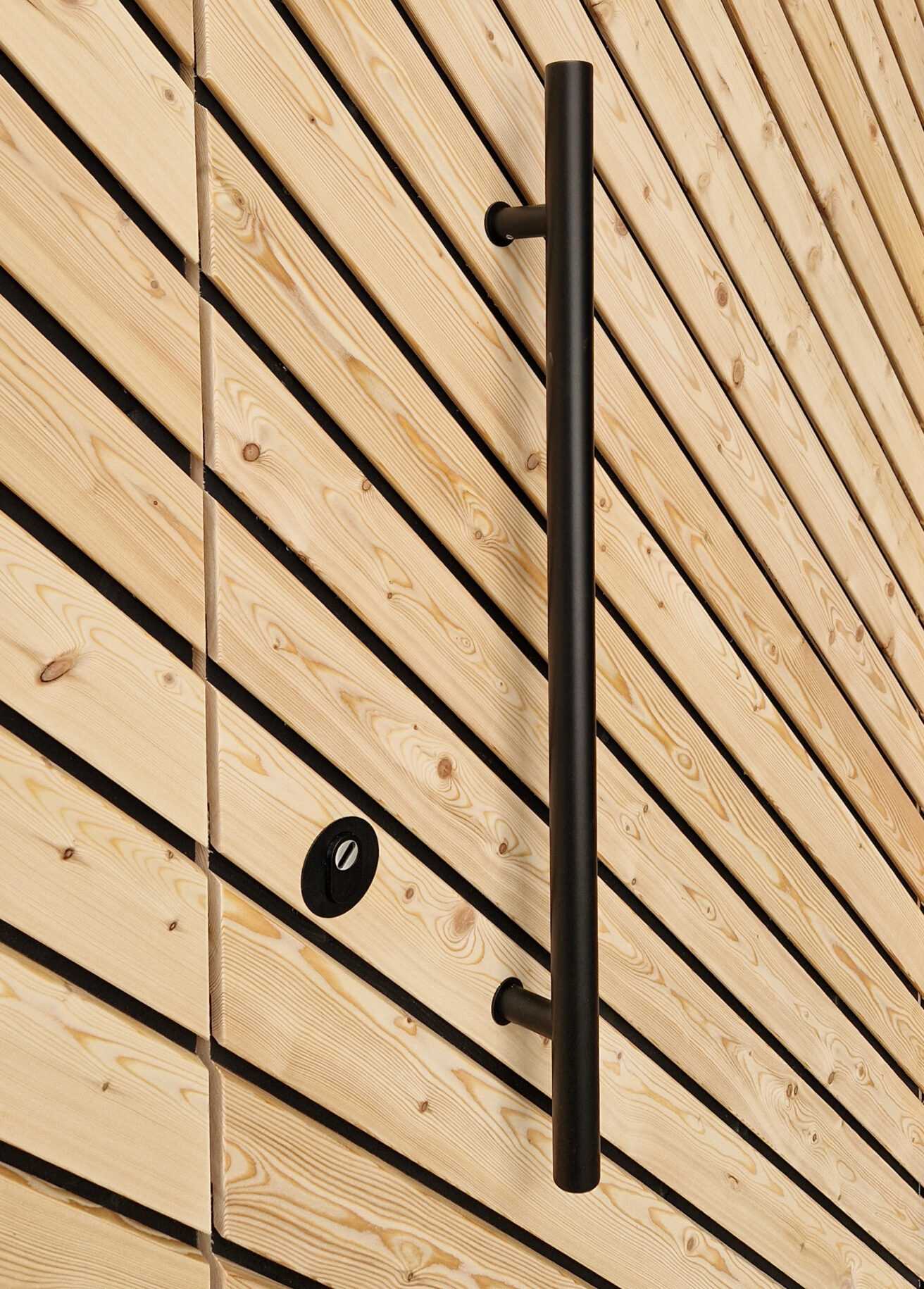 Black handle on concealed door with angled wooden slats